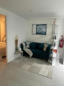a living room with a green couch and a bed at Portu Sereno Apartments in Setúbal