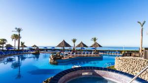 a pool at a resort with the ocean in the background at Apartamento superior con balcon en Bahia Feliz in Playa del Aguila