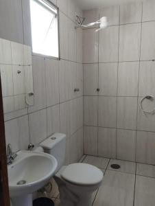 a white bathroom with a toilet and a sink at Apartamento Laranja Matão in Matão