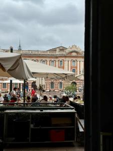 a group of people sitting at tables in front of a building at Studio place du Capitole climatisation in Toulouse