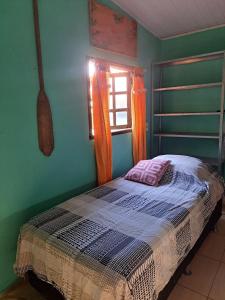 a bed in a green room with a window at Casa Moreira Melo in Pirenópolis