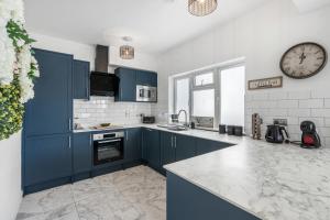 una cocina con armarios azules y un reloj en la pared en Clarence Square 2 Bedroom Central, en Brighton & Hove 18 fotos más
