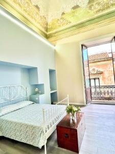 a bedroom with a white bed and a large window at Dimora degli Affreschi in Riposto