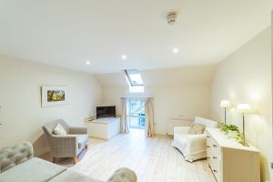 a living room with white furniture and a tv at Penninghame Estate - Wallace Apartment in Challoch