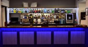 Eine Bar mit blauem Licht in einem Raum mit Alkohol in der Unterkunft Ashley Court Hotel in Andover + 20 Fotos