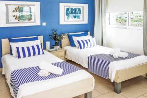 two beds in a room with blue walls at Villa Elena Coral in Peyia +20 photos