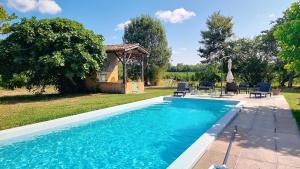 a swimming pool with chairs and a gazebo at Ferme de Mouline in Sainte-Foy-la-Longue