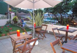 un patio avec tables, chaises et un parasol dans l'établissement Inn House Santa Teresa, à Rio de Janeiro