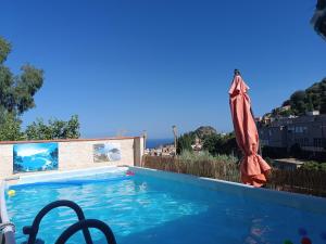 a large swimming pool with an umbrella and a swimming pool at Le Grand Soleil Apartments in Taormina