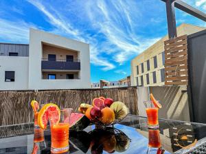 a glass table with fruit and juice on a balcony at Védas Prestige, Tout confort in Saint-Jean-de-Védas
