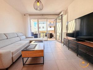 a living room with a couch and a flat screen tv at Védas Prestige, Tout confort in Saint-Jean-de-Védas