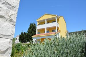 un bâtiment jaune et blanc au sommet d'une colline dans l'établissement Apartments Buturi, à Soline