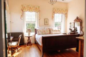 a bedroom with a large bed and two windows at Ironclad Inn and Bourbon Room in Fredericksburg