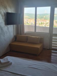 Una sala de estar con un sofá y una ventana grande. en Апартаменти Ванкови, en Veliko Tŭrnovo
