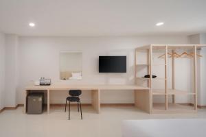 a room with a desk with a tv on a wall at Cloud9 Stay Chiang Mai in Chiang Mai