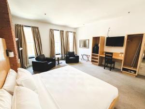 a living room with a white bed and a television at The Franklin Hotel in St. John's