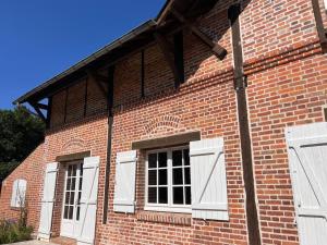 a brick building with two windows and white doors at Domaine en Sologne Piscine chambre Climatisée in Nouan-le-Fuzelier
