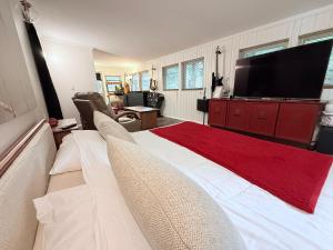 Schlafzimmer mit einem großen weißen Bett und einem Flachbild-TV in der Unterkunft Charming Romantic Lakefront Cottage or Guest Room Depending on Availability Near Golf in Anderson