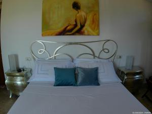 a white bed with two blue pillows and a painting at Locazione Turistica Spaccarotella Terrazzo con Vista su Gualdo Cattaneo in Gualdo Cattaneo