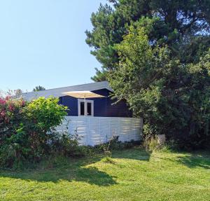 a house with a white fence in a yard at Charmerende Norsk Bjælkehytte med fibernet in Slagelse