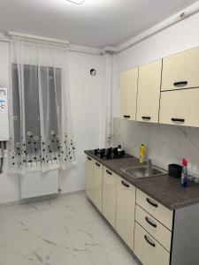 a kitchen with white cabinets and a sink at Atlantis Suites Bragadiru Bucuresti Parcare gratuita Self checkin in Bragadiru