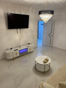 a living room with a tv and a couch and a table at Atlantis Suites Bragadiru Bucuresti Parcare gratuita Self checkin in Bragadiru