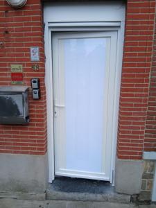 a white door on a brick building with a tv at Maison Jardin aéroport Charleroi in Charleroi