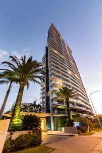 a tall building with palm trees in front of it at Artique Surfers Paradise - Official in Gold Coast