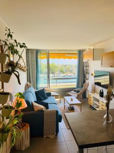 a living room with a blue couch and a large window at La Lagune in Le Grau-du-Roi
