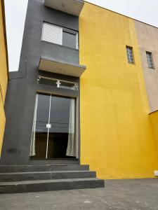 Un edificio amarillo y gris con una cruz en la ventana. en Conforto a 8min da Canção Nova com Garagem, en Cachoeira Paulista