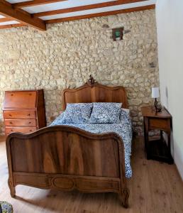 a bedroom with a wooden bed and a stone wall at Gîte Belle, Piscine privée, vue sur la campagne in Nonac +36 photos