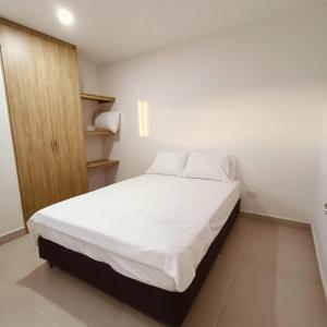 a bedroom with a white bed and a wooden cabinet at Aviva Sierra 1804 in Santa Marta