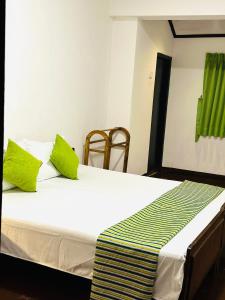 a bed with two green pillows on top of it at Rosewood Bungalow in Bandarawela