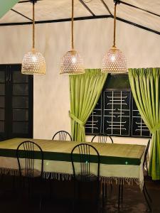 a dining table with chairs and two chandeliers at Rosewood Bungalow in Bandarawela