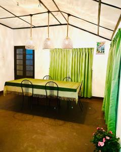 a dining room with a green table and chairs at Rosewood Bungalow in Bandarawela