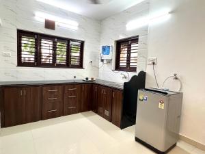 a kitchen with wooden cabinets and a refrigerator at Nisarg Homestay with Kitchen Dinning in Bhuj