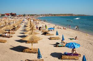 a beach with lots of chairs and umbrellas at Casa Noastra in Vama Veche