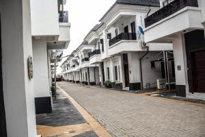an empty street with a row of white buildings at 4 Bedroom Orchid Haven Home With High Speed WiFi and free Parking with Long Stay Ready in Ikota
