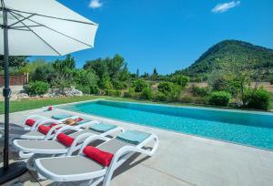 Un grupo de sillas y una sombrilla junto a una piscina. en Owl Booking Villa La Rafal - Luxury Retreat with Mountain Views, en Port de Pollença (Puerto Pollensa)