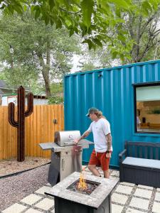 科罗拉多斯普林斯Cargo Casita Shipping Container Tiny Home的后院的烤架上的人做饭