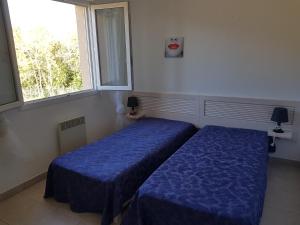 two beds in a room with a window at Casa di u sole in Santa-Maria-Poggio