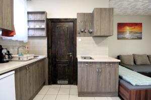 a kitchen with wooden cabinets and a sink and a couch at Áron Apartment in Nyíregyháza