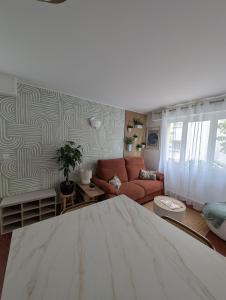 a living room with a couch and a living room with a table at Le Manoa Foncillon Parking privé in Royan