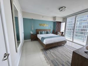 a bedroom with a bed and blue walls and windows at Sun&Sea IconBrickell Unit in Miami +38 photos