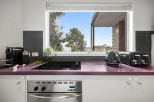 a kitchen with a stove top oven next to a window at Comfy Box Hill Unit Near Station and Restaurants in Box Hill