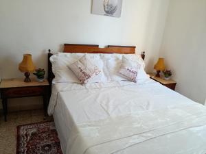 a white bed with white sheets and pillows on it at Casa Vacanza Arzello in Melazzo