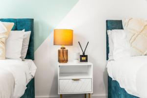a bedroom with two beds and a nightstand with a lamp at Stylish, 2-Bedroom Apartment for 4, Free PaModern 2-Bedroom Flat, Accommodates 4, Free Parking, Wi-Fi, Ideal for Families, City Centrerking, & Wi-Fi, Family-Friendly, City Centre in Liverpool +21 photos