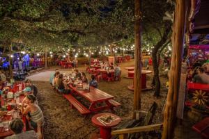 a group of people sitting at tables in a park at night at The Cozy Corner in Windermere Oaks on Lake Travis in Spicewood +59 photos