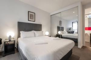 Un dormitorio con una gran cama blanca y un espejo. en St Kilda Penthouse. Views. Spa., en Melbourne
