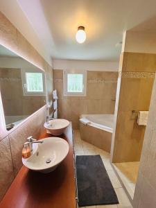 un bagno con due lavandini, una doccia e una vasca di La Villa du vignoble Piscine a Hermonville